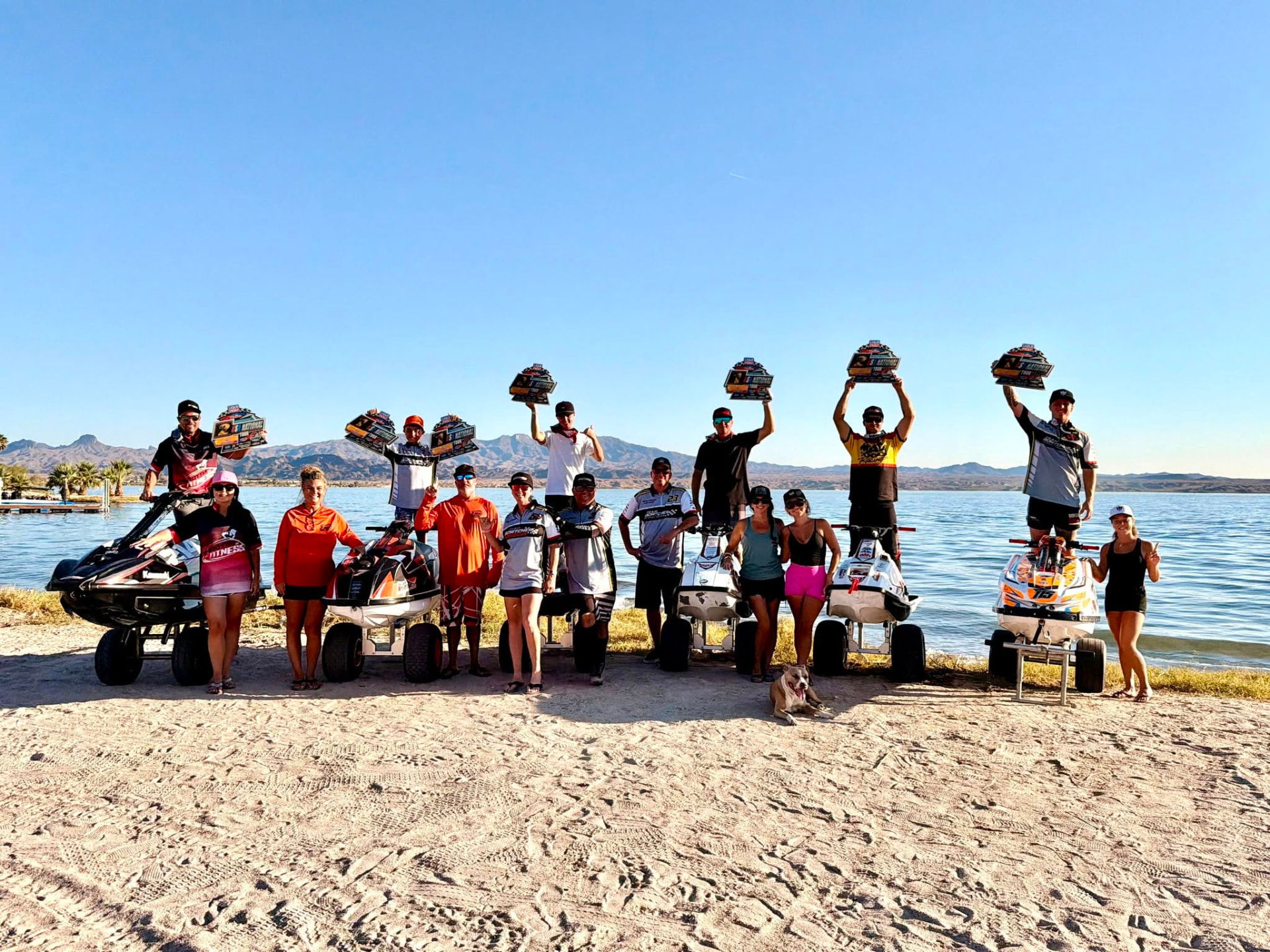Team Goatcher Racing riders and crew celebrating on the beach at Lake Havasu with their jet skis