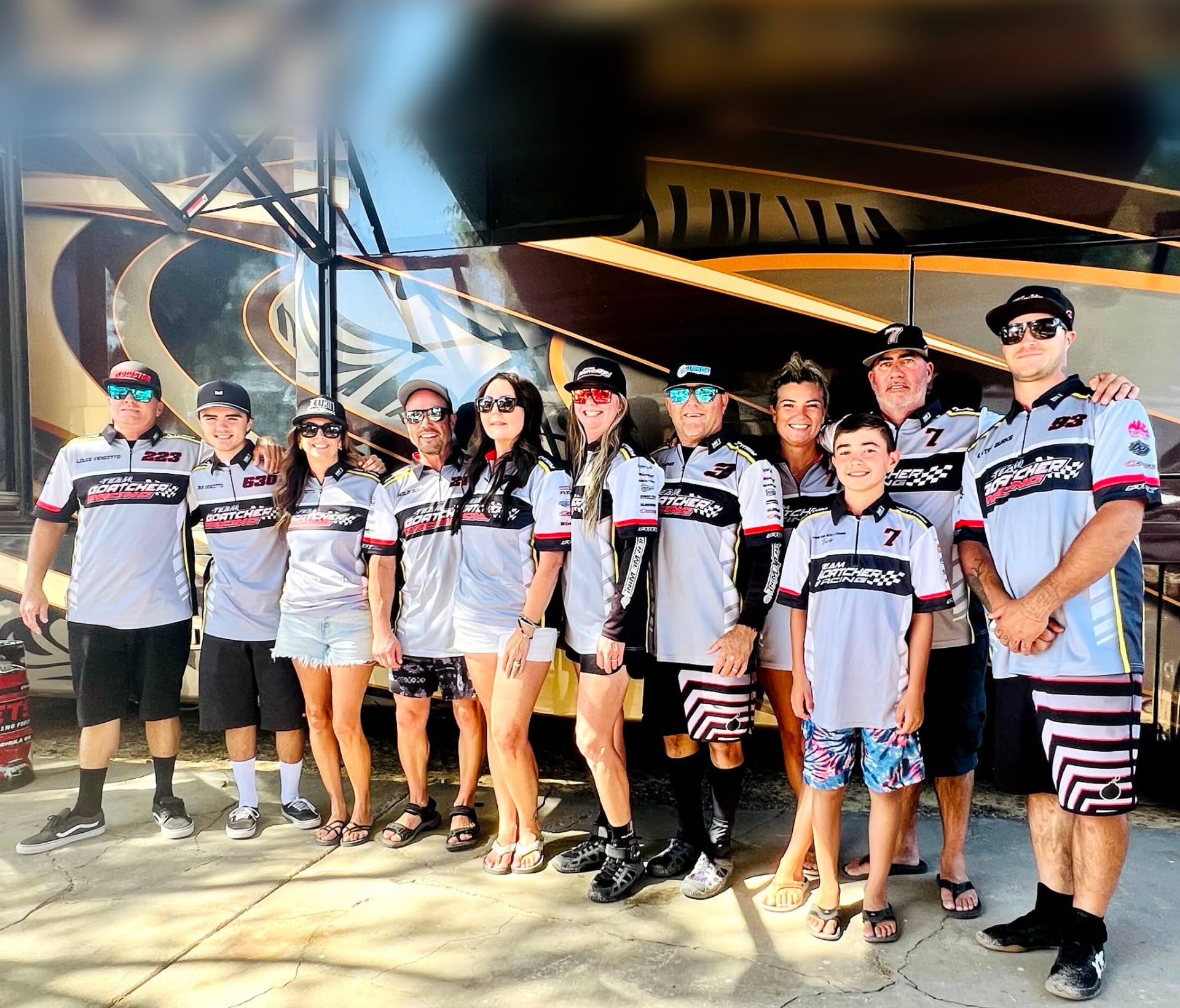 Team Goatcher Racing crew and riders in team shirts in front of the race trailer